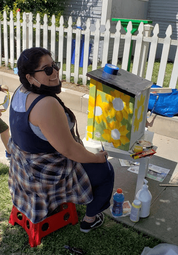 Alaina paints flowers on Free Food Pantry